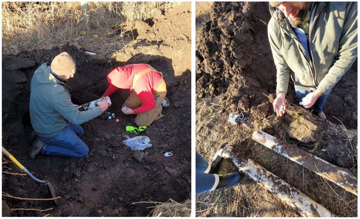 Two men in the ditch holding the white plastic with the silver